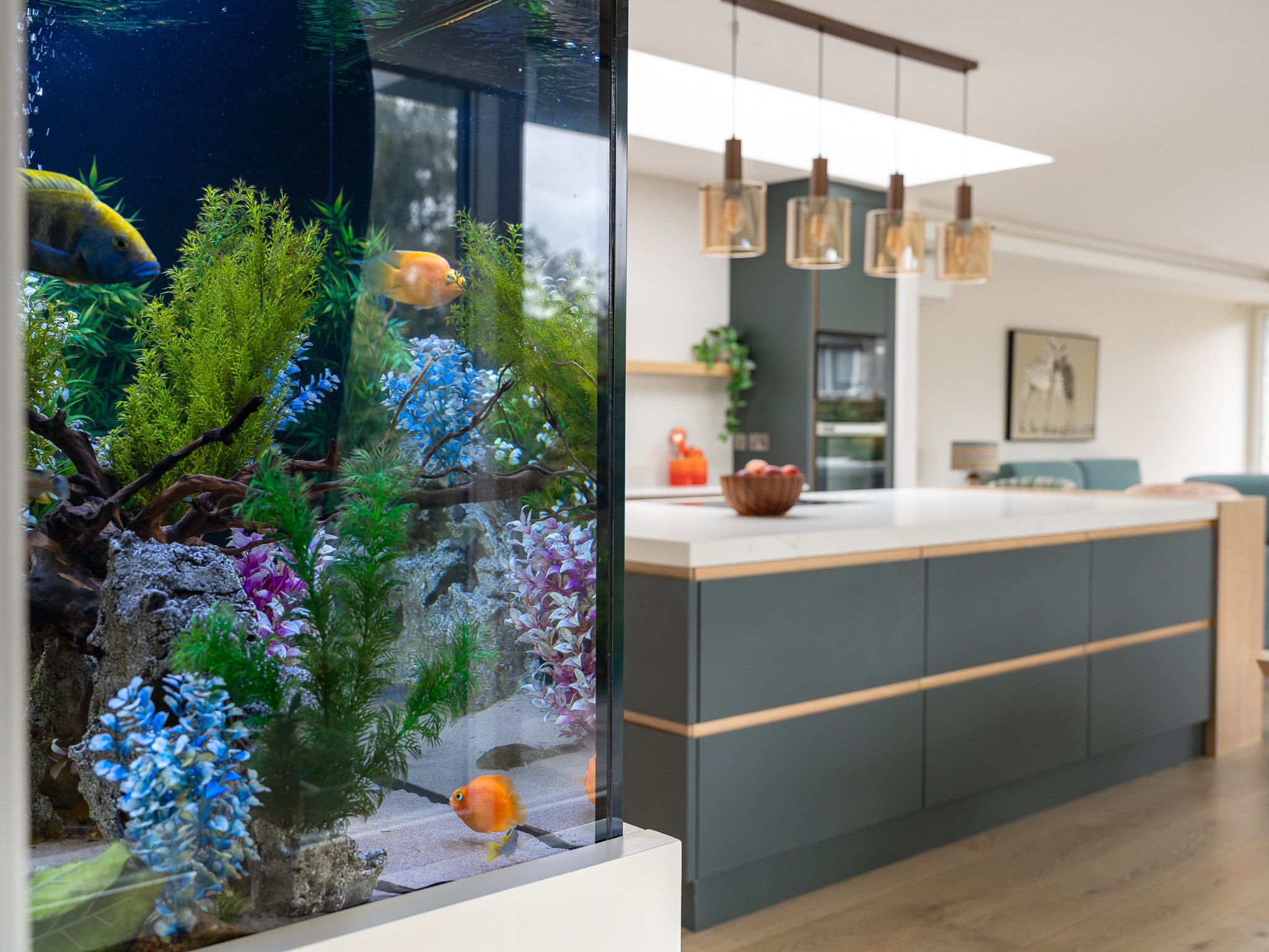 Integrated aquarium beside a handleless kitchen island in deep teal
